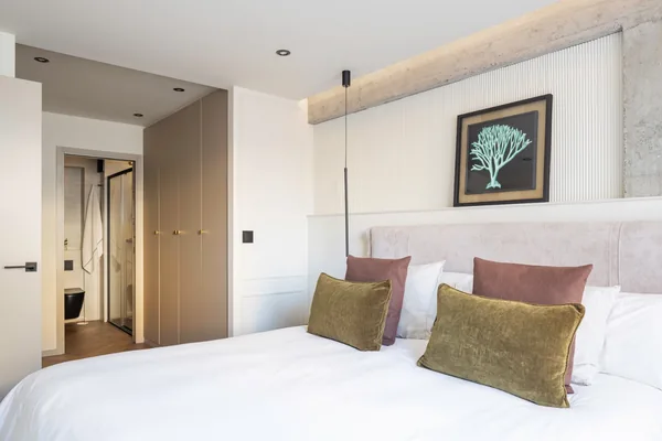 Dormitorio con cabecero tapizado y cojines verdes